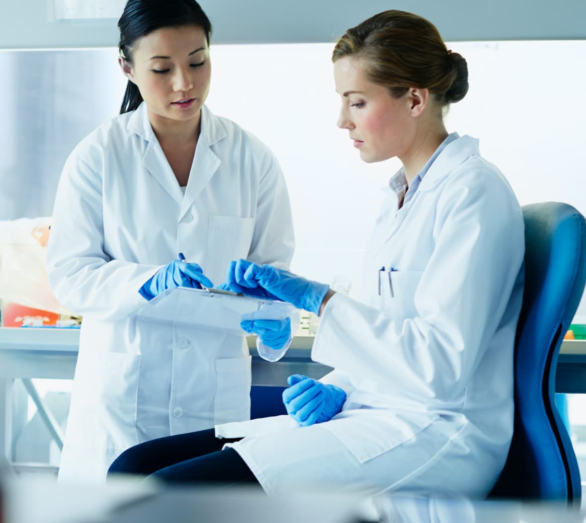 Two female scientists talking over clipboard