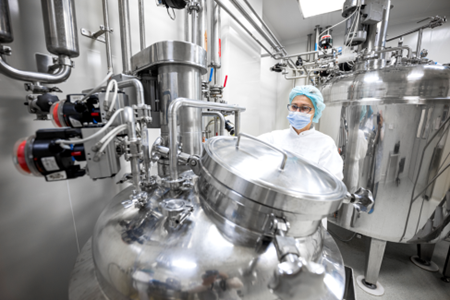 Image of woman looking at equipment in the monoclonal antibody manufacturing facility at GBI.